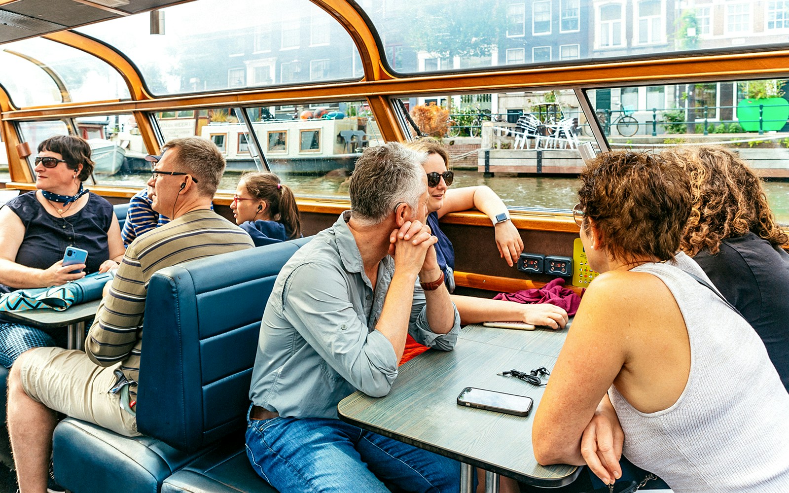 Canal boat cruising through Amsterdam city center with historic buildings and bridges in view.