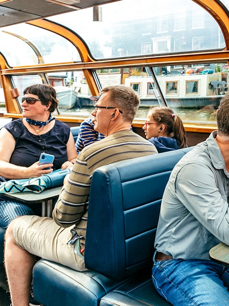 Tourists enjoying a canal cruise in Amsterdam, viewing city architecture.
