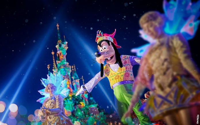 Disneyland Paris night show with Goofy and performers in front of illuminated castle.