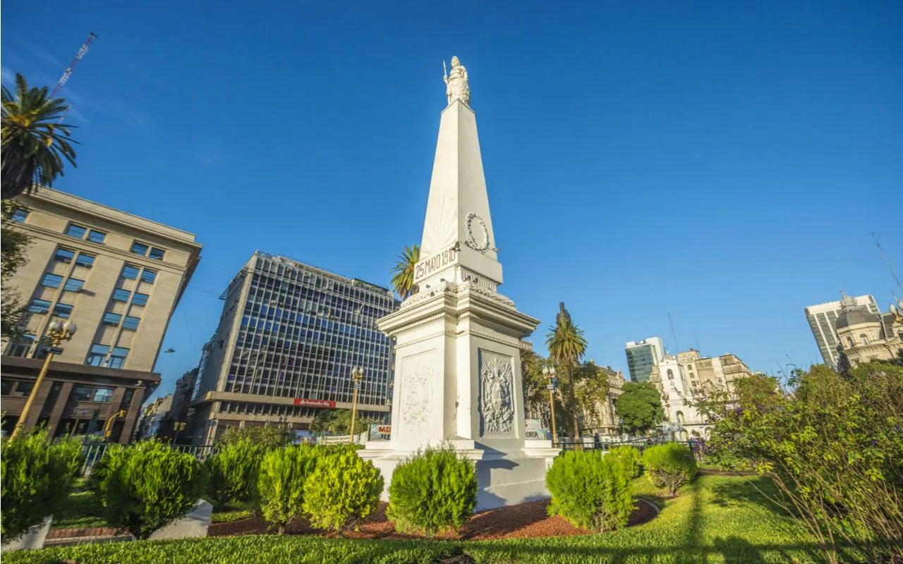 Obelisk on Avenida de Mayo surrounded by buildings and greenery, Buenos Aires.
