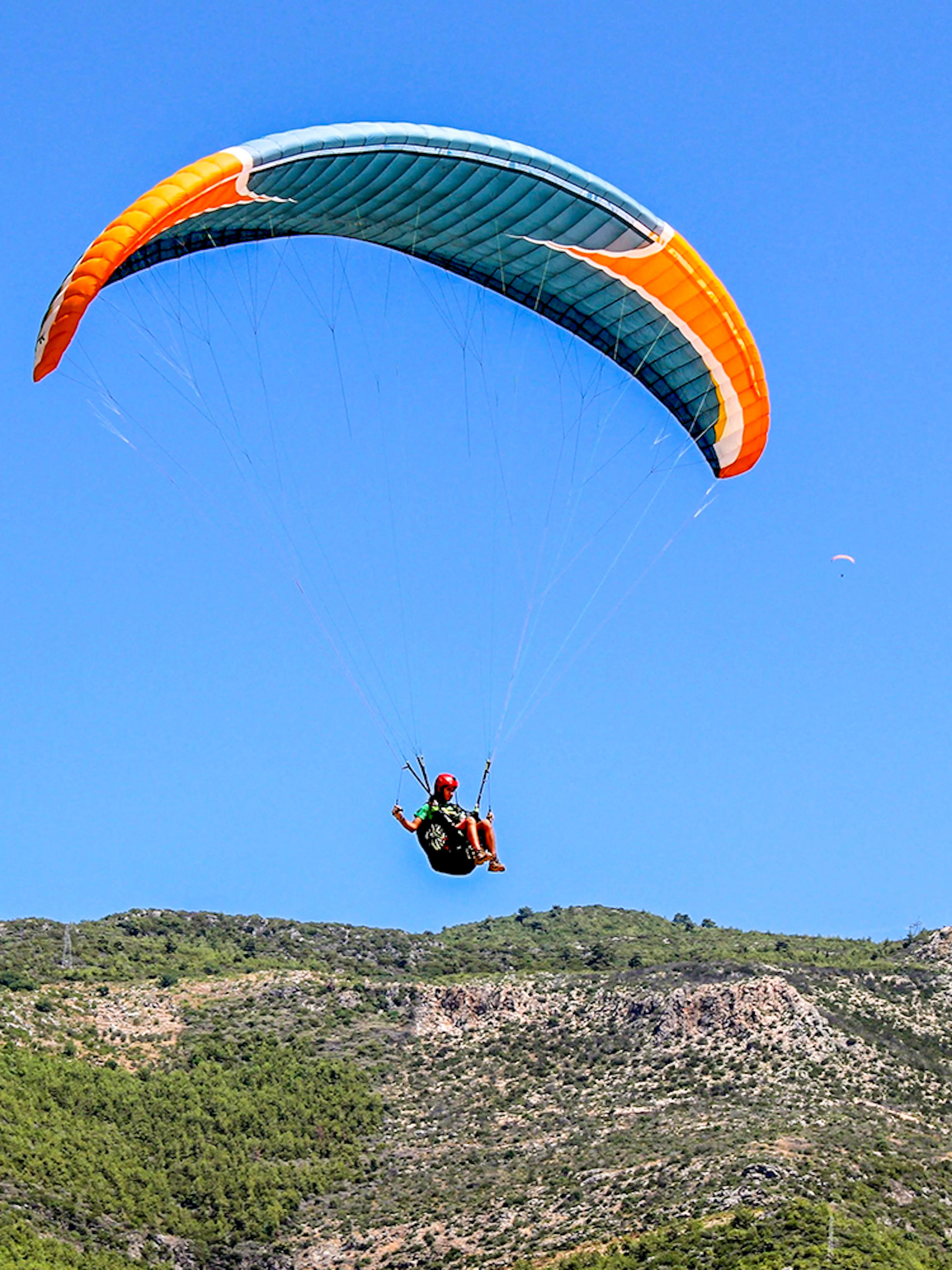 Paraglider soaring over green hills in Alanya, Turkey.