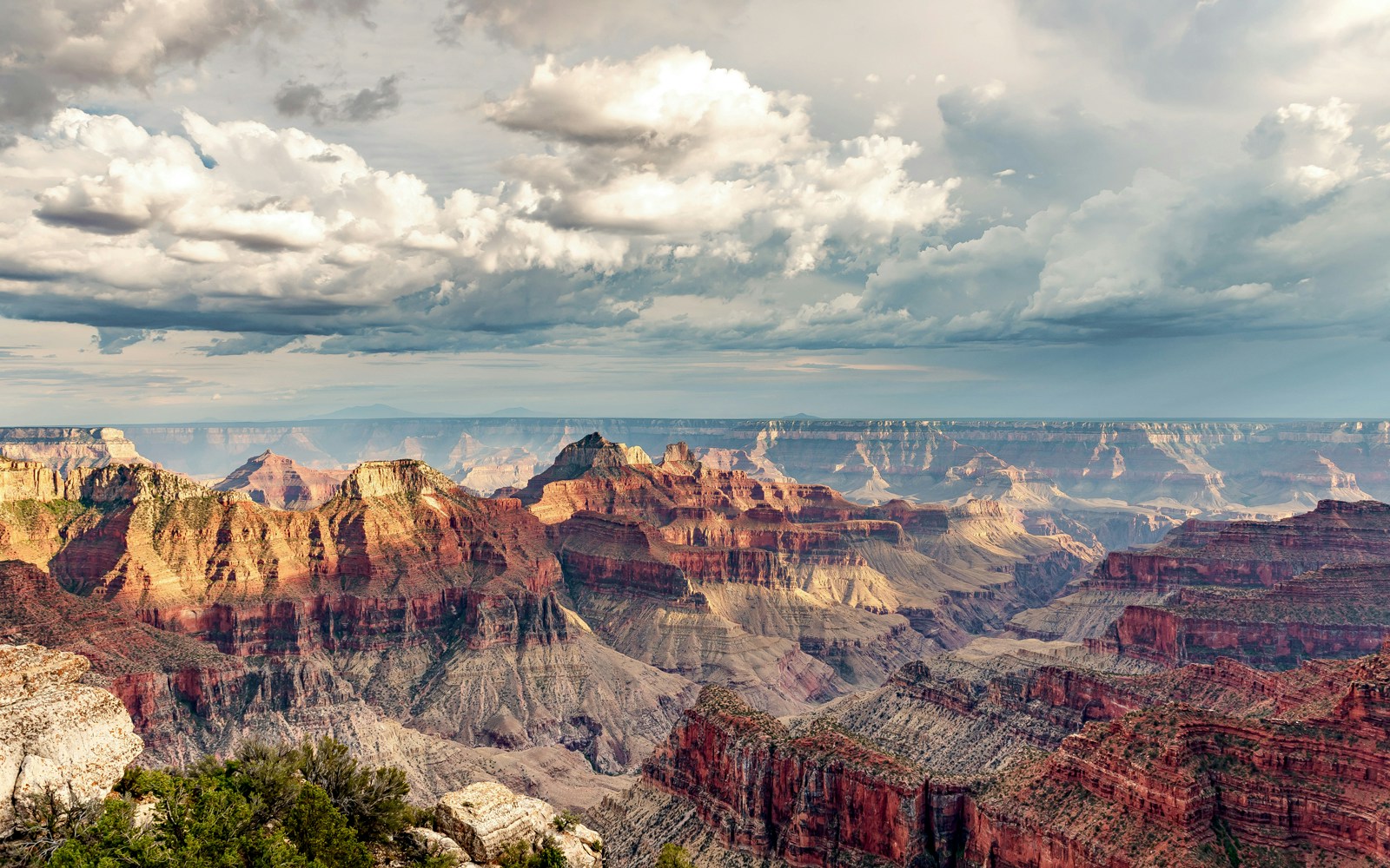 Man sitting on the edge of the Grand Canyon, Arizona, overlooking vast canyon landscape.