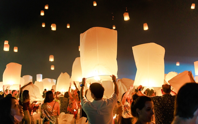 People releasing lanterns into the night sky at Chiang Mai Sky Lanterns Festival 2025.