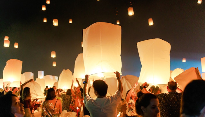 People releasing lanterns into the night sky at Chiang Mai Sky Lanterns Festival 2025.