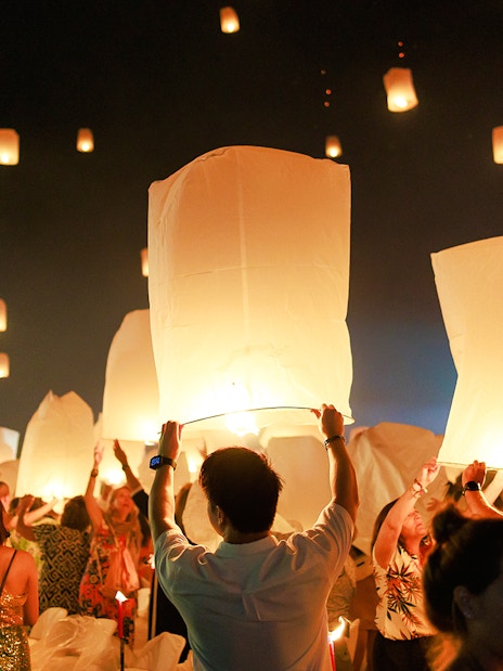 People releasing lanterns into the night sky at Chiang Mai Sky Lanterns Festival 2025.