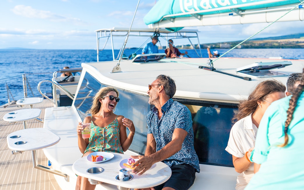 Couple enjoying drinks and snacks on a luxury sailboat during a snorkel tour in Maui, Hawaii.