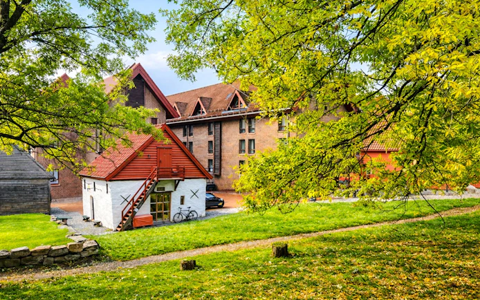 Historic wooden buildings in Bryggen, Bergen, surrounded by lush greenery.