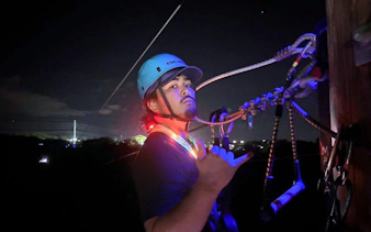 Person preparing for night zipline adventure with city lights in the background.