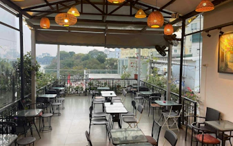 Rooftop café with empty tables overlooking Hanoi Old Quarter, part of self-guided city exploration game.