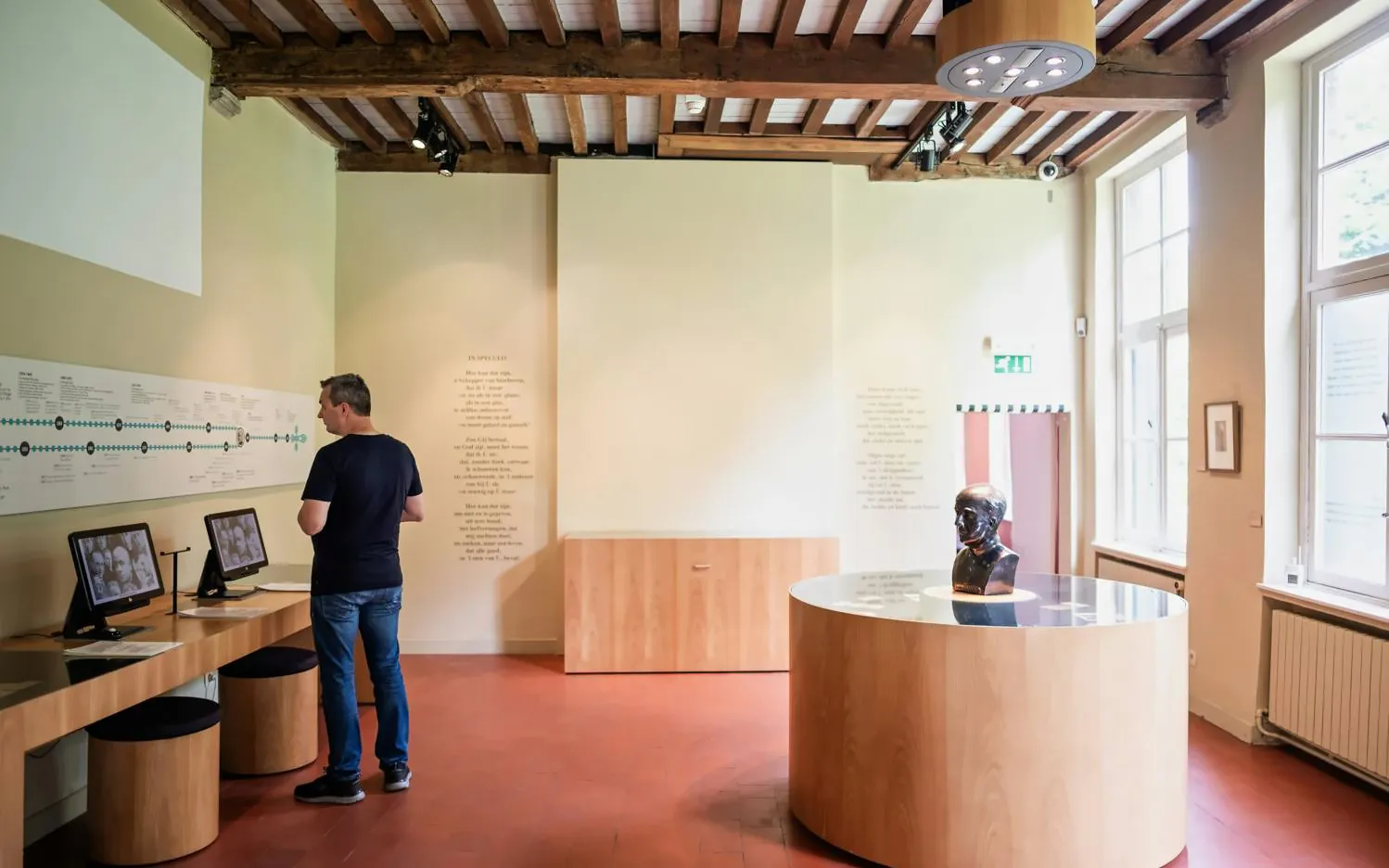 Man exploring exhibits at Gezellehuis museum, featuring interactive displays and a bust.