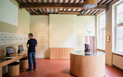 Man exploring exhibits at Gezellehuis museum, featuring interactive displays and a bust.