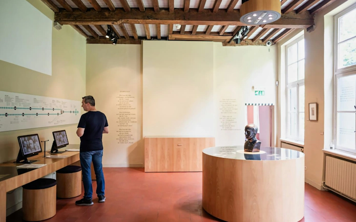 Man exploring exhibits at Gezellehuis museum, featuring interactive displays and a bust.