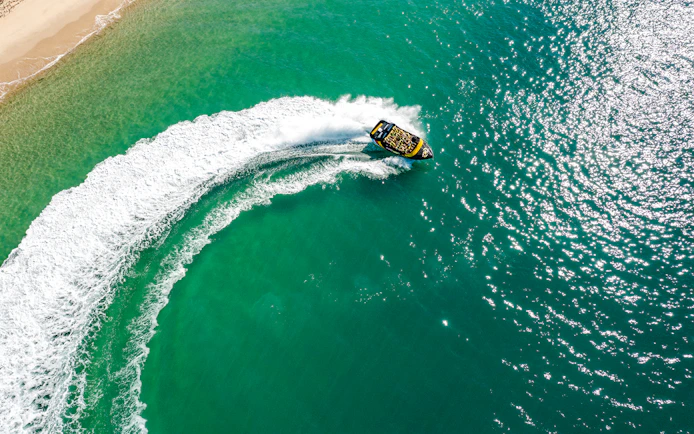 Jet boat making a sharp turn on turquoise waters of Gold Coast.