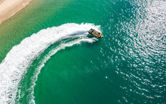 Jet boat making a sharp turn on turquoise waters of Gold Coast.