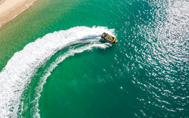 Jet boat making a sharp turn on turquoise waters of Gold Coast.