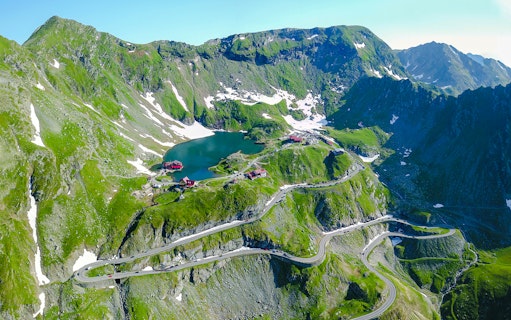 Transfăgărășan Road winding through the Carpathian Mountains, Romania, near a mountain lake.