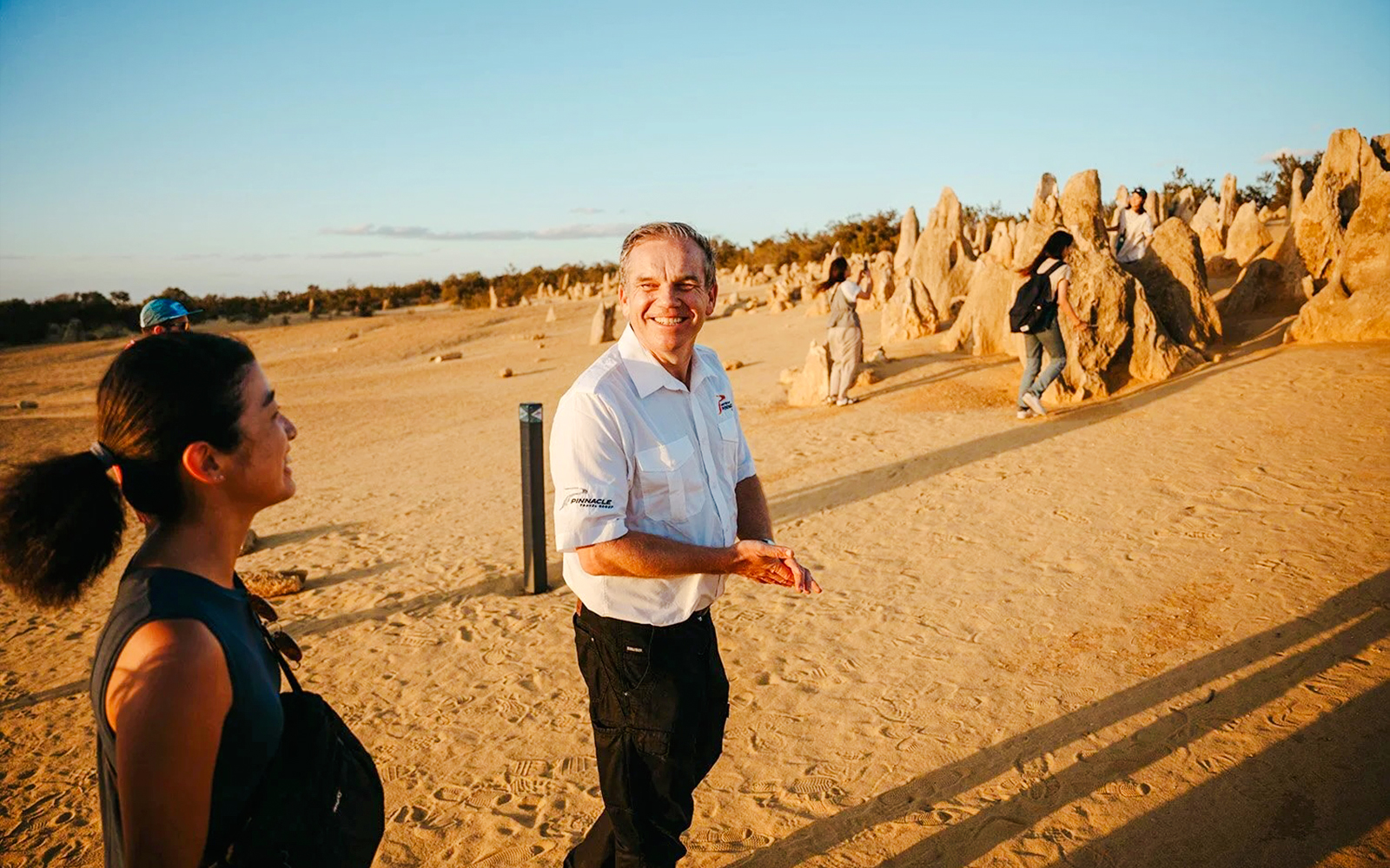 Tour guide leading visitors through Pinnacles Desert at sunset, Western Australia.