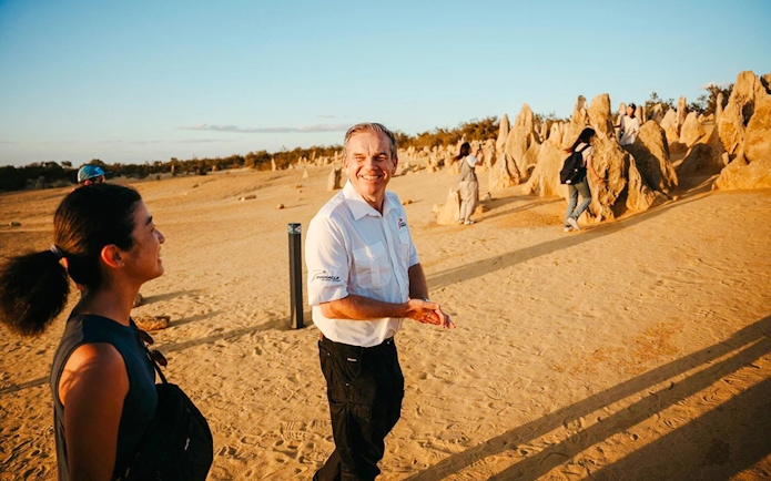 Tour guide leading visitors through Pinnacles Desert at sunset, Western Australia.