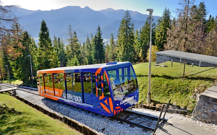 Cable car ascending in Tatra Mountains, Zakopane, surrounded by trees and mountain views.