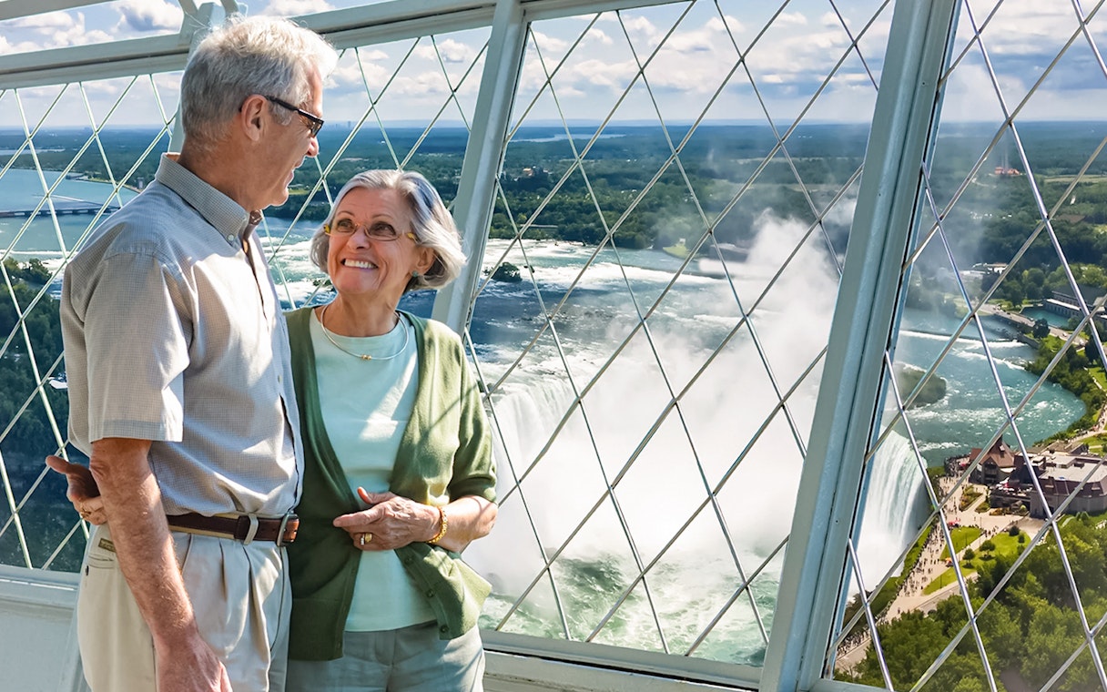 Tourists enjoying Niagara Falls view from Skylon Tower observation deck.