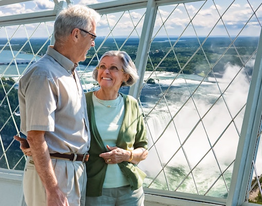 Tourists enjoying Niagara Falls view from Skylon Tower observation deck.