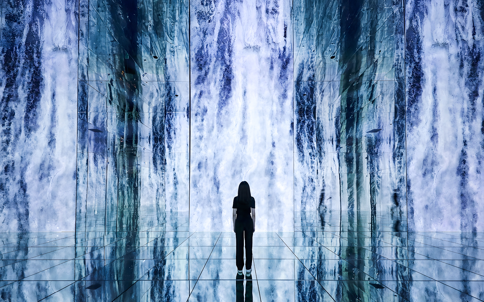 Person standing in front of digital waterfall display at ARTE Museum.
