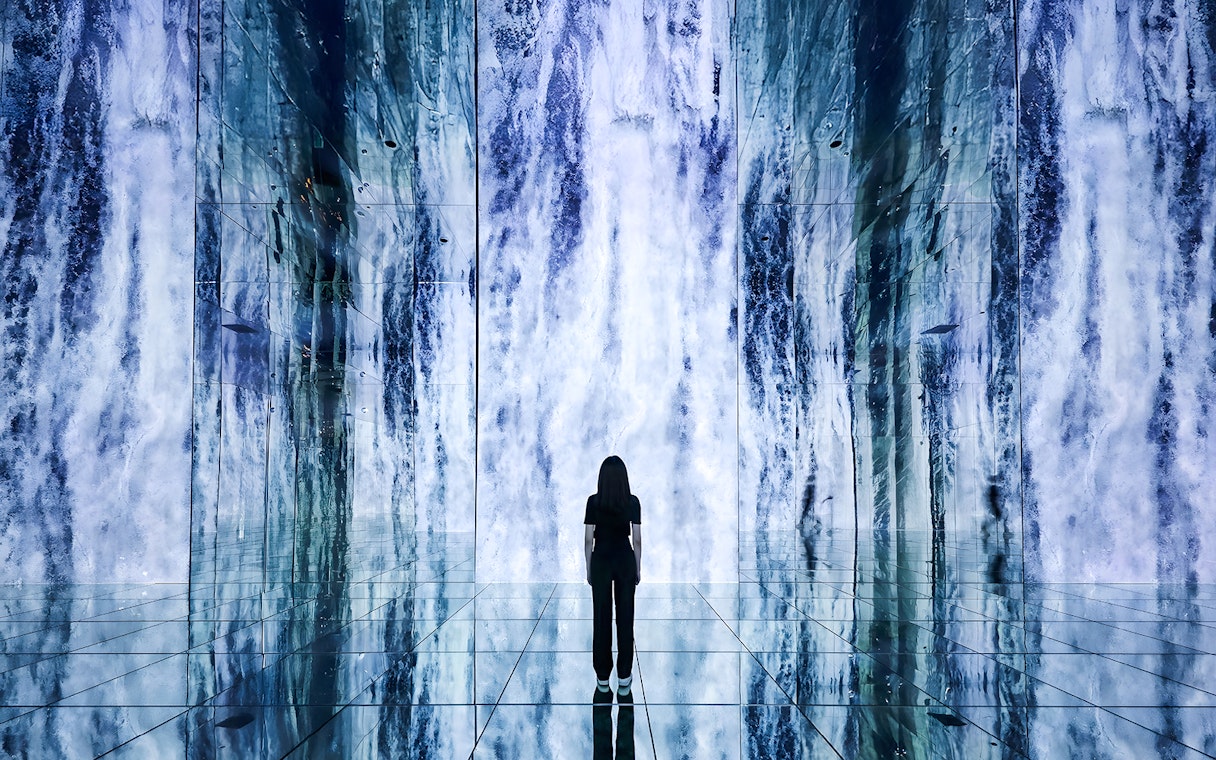 Person standing in front of digital waterfall display at ARTE Museum.
