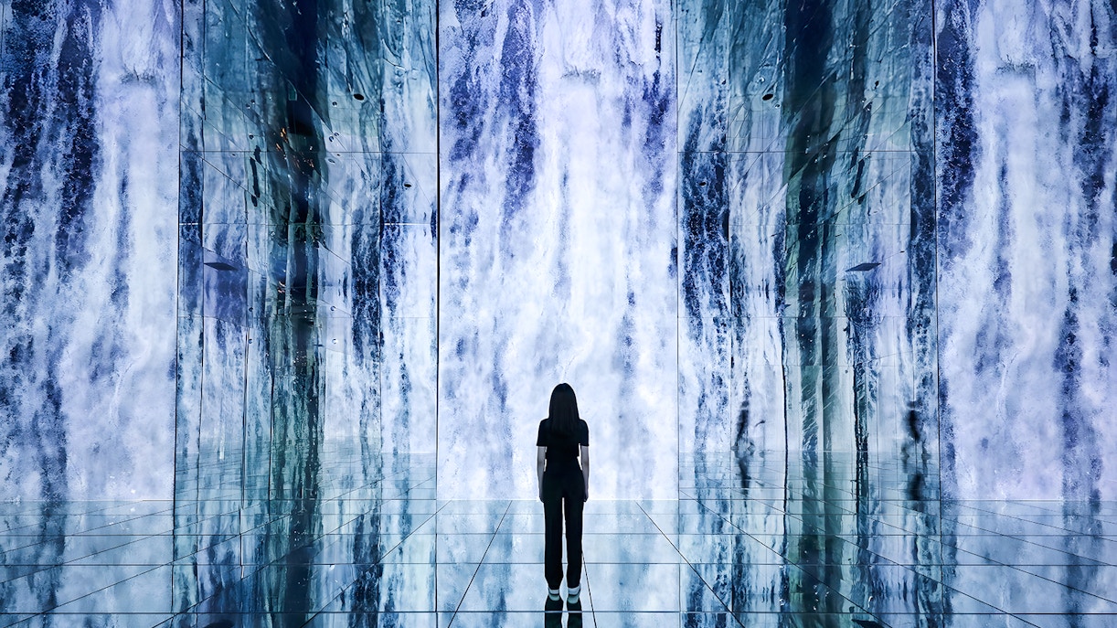 Person standing in front of digital waterfall display at ARTE Museum.