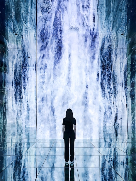Person standing in front of digital waterfall display at ARTE Museum.