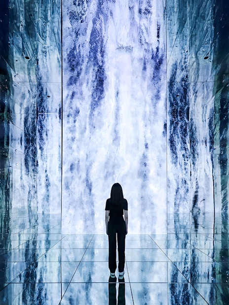 Person standing in front of digital waterfall display at ARTE Museum.