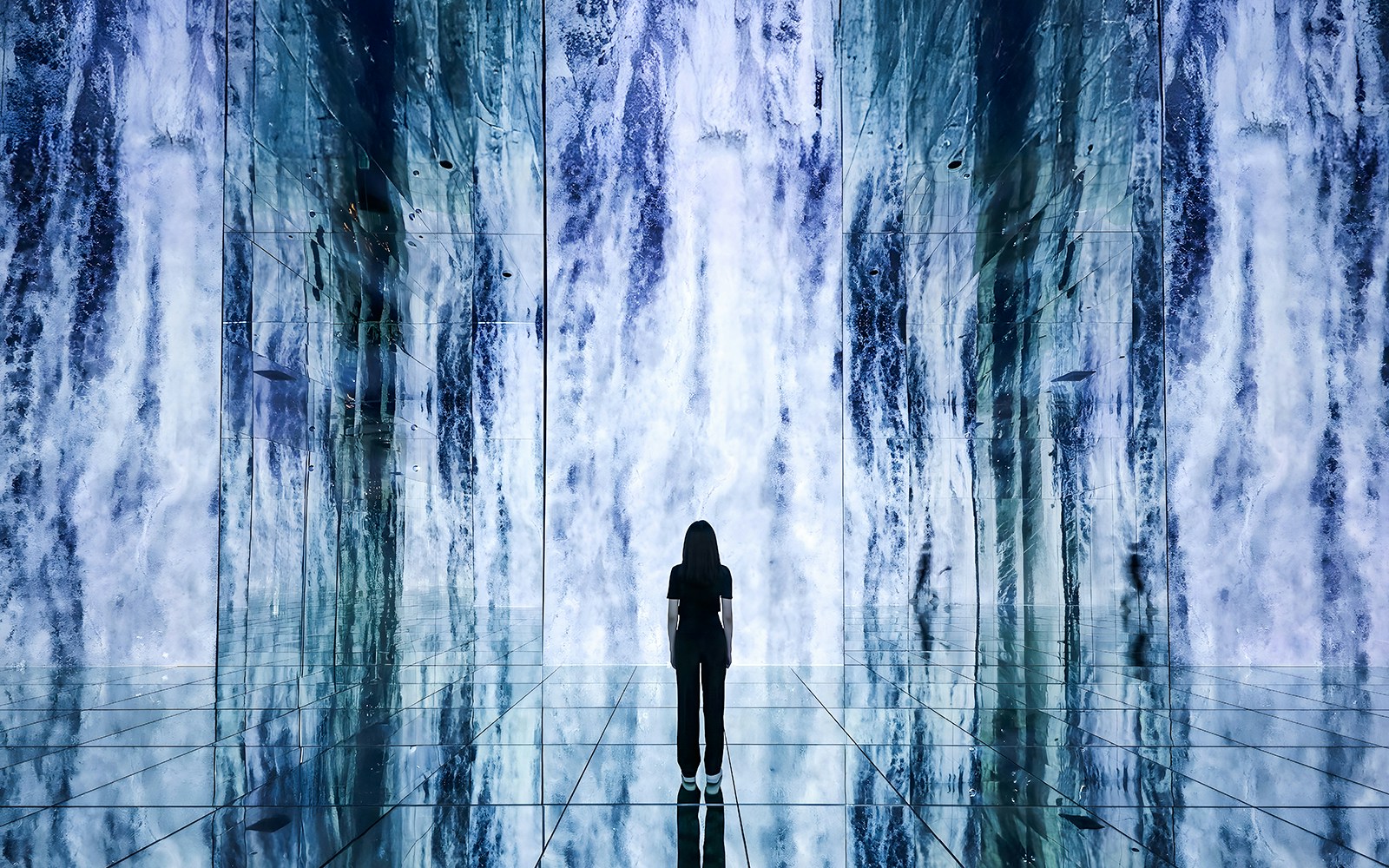 Person standing in front of digital waterfall display at ARTE Museum.