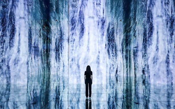 Person standing in front of digital waterfall display at ARTE Museum.