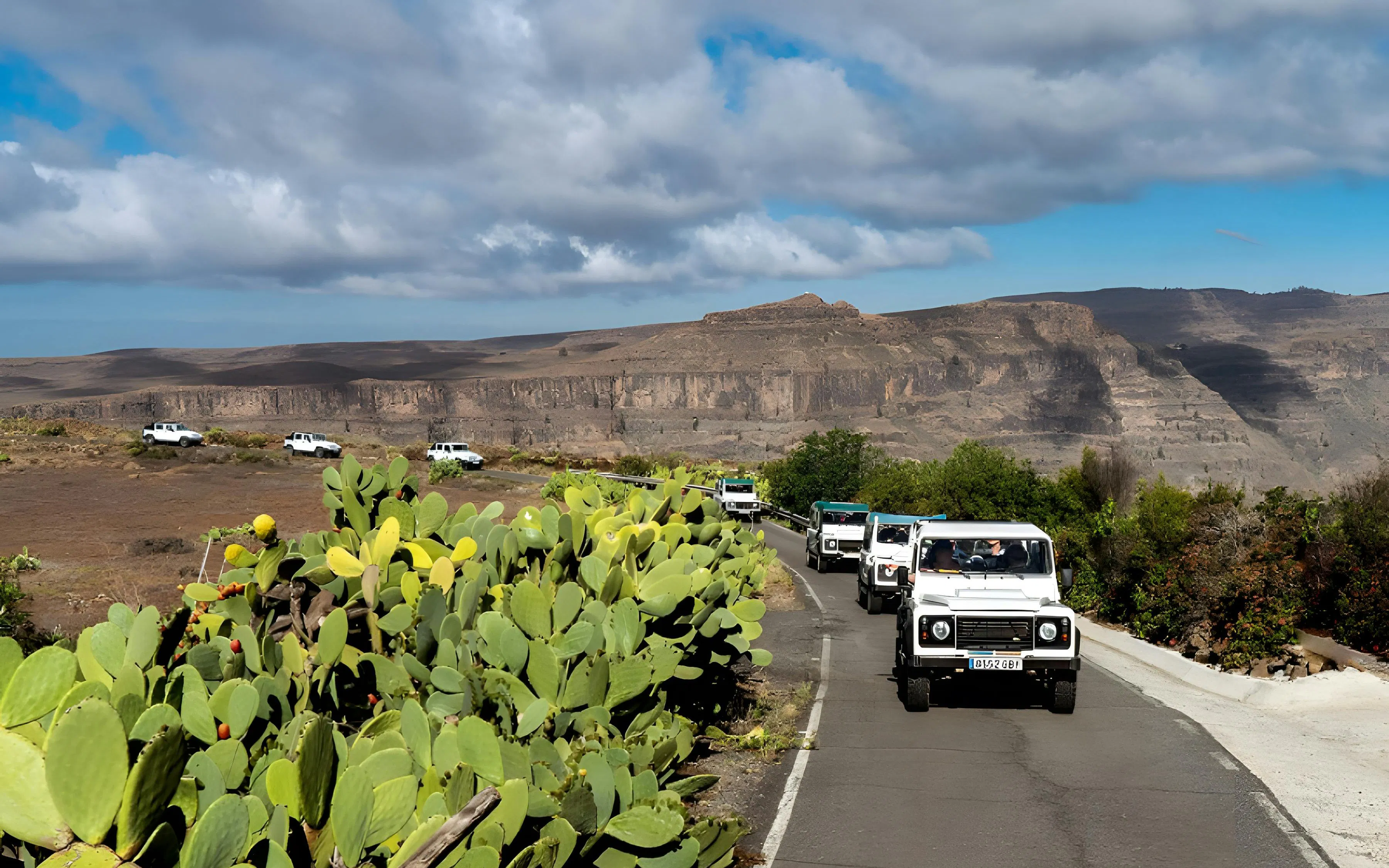 Jeep convoy on a scenic road in Gran Canaria with mountainous landscape.