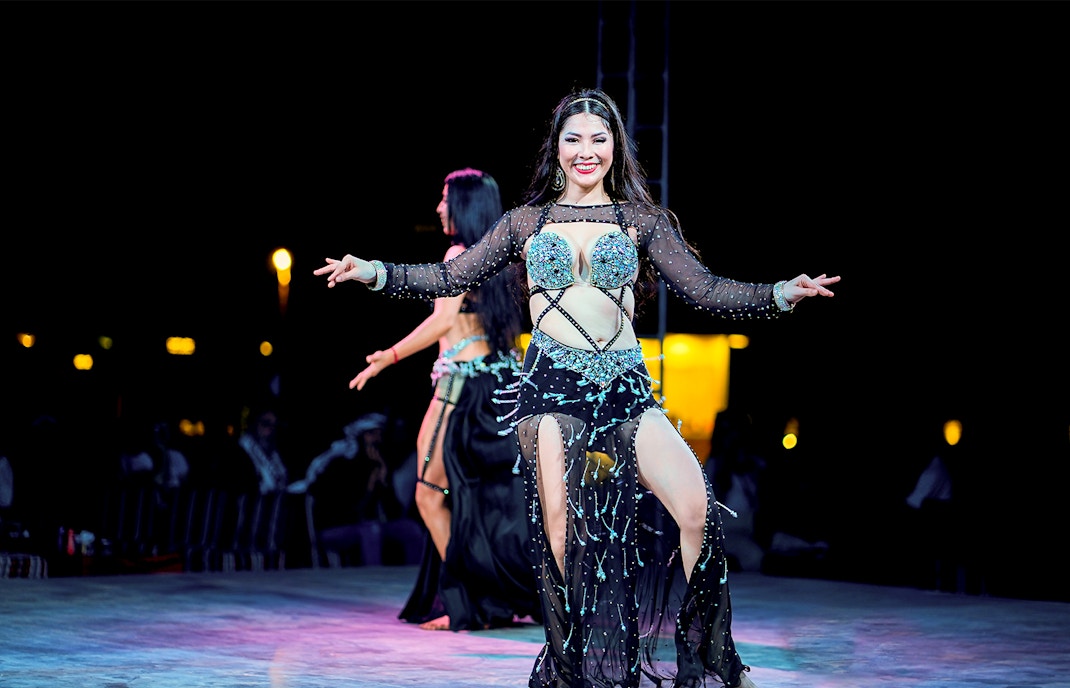 Woman performing traditional dance at Dubai desert safari experience.