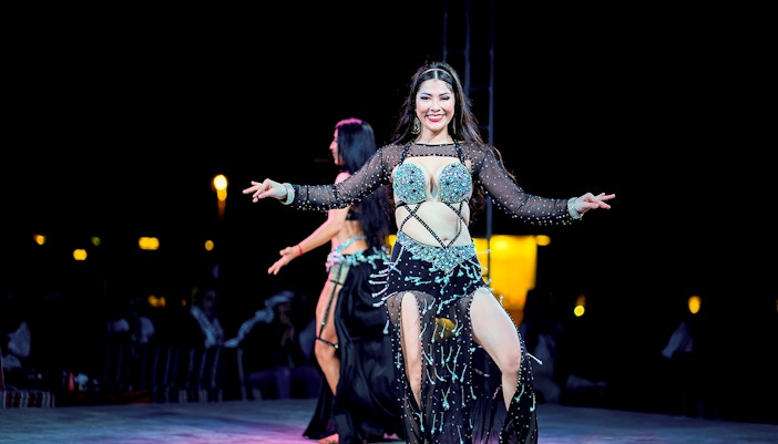 Woman dancing at Dubai desert safari experience.