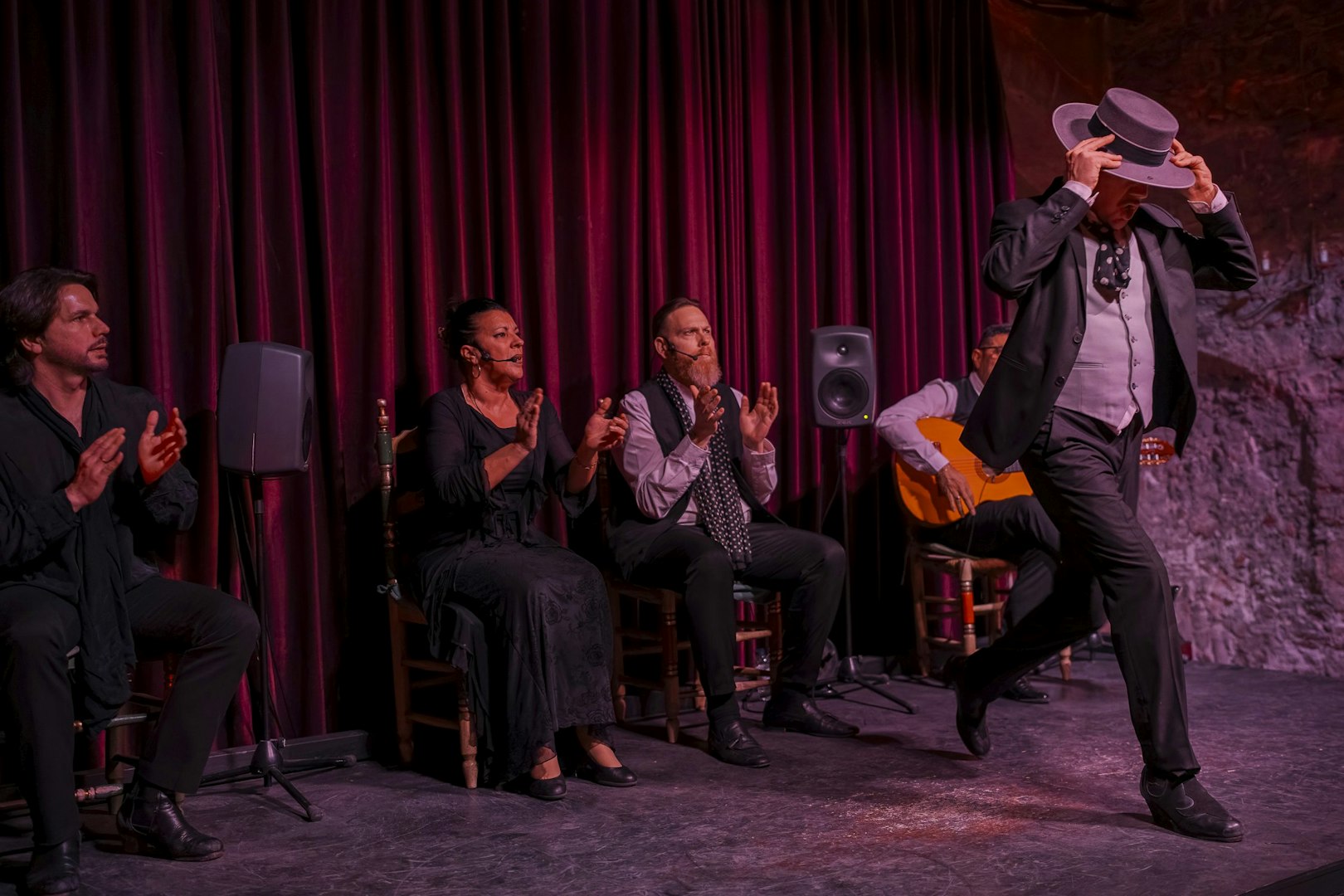 Flamenco dancer performing at Palau Dalmases with musicians clapping and playing guitar.