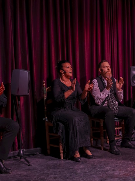 Flamenco dancer performing at Palau Dalmases with musicians clapping and playing guitar.