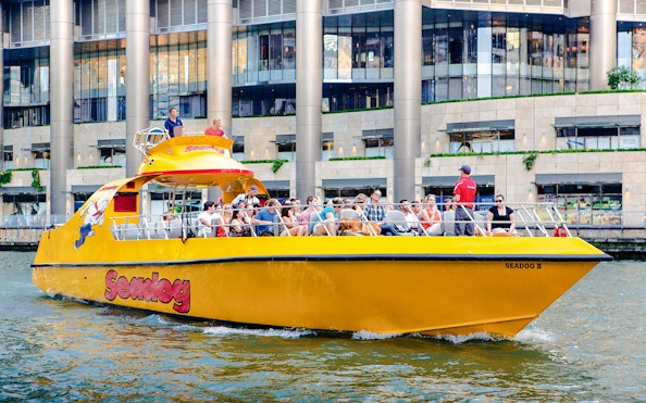 Tourists enjoying Sea Dog Cruise on Lake Michigan near city buildings.