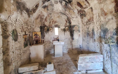 Interior of a stone room with ancient frescoes and religious icons at Phaistos Palace, Crete.