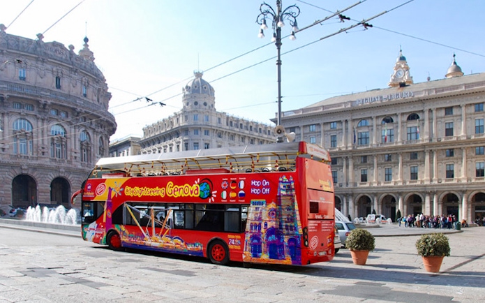 Hop-On Hop-Off bus in Genoa's Piazza De Ferrari with historic buildings.
