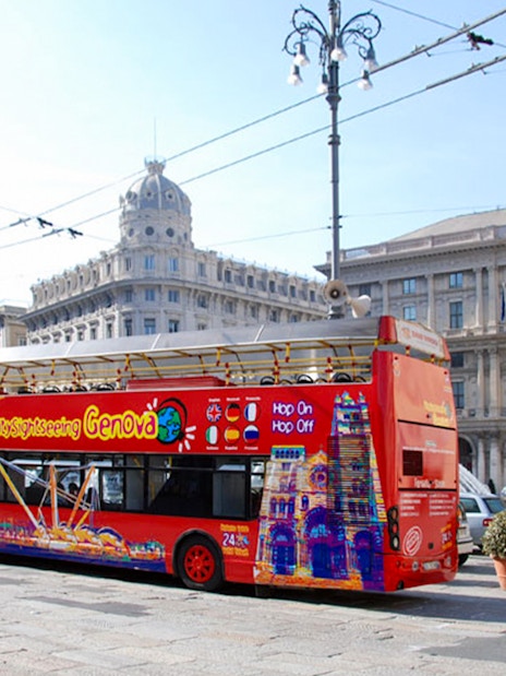 Hop-On Hop-Off bus in Genoa's Piazza De Ferrari with historic buildings.