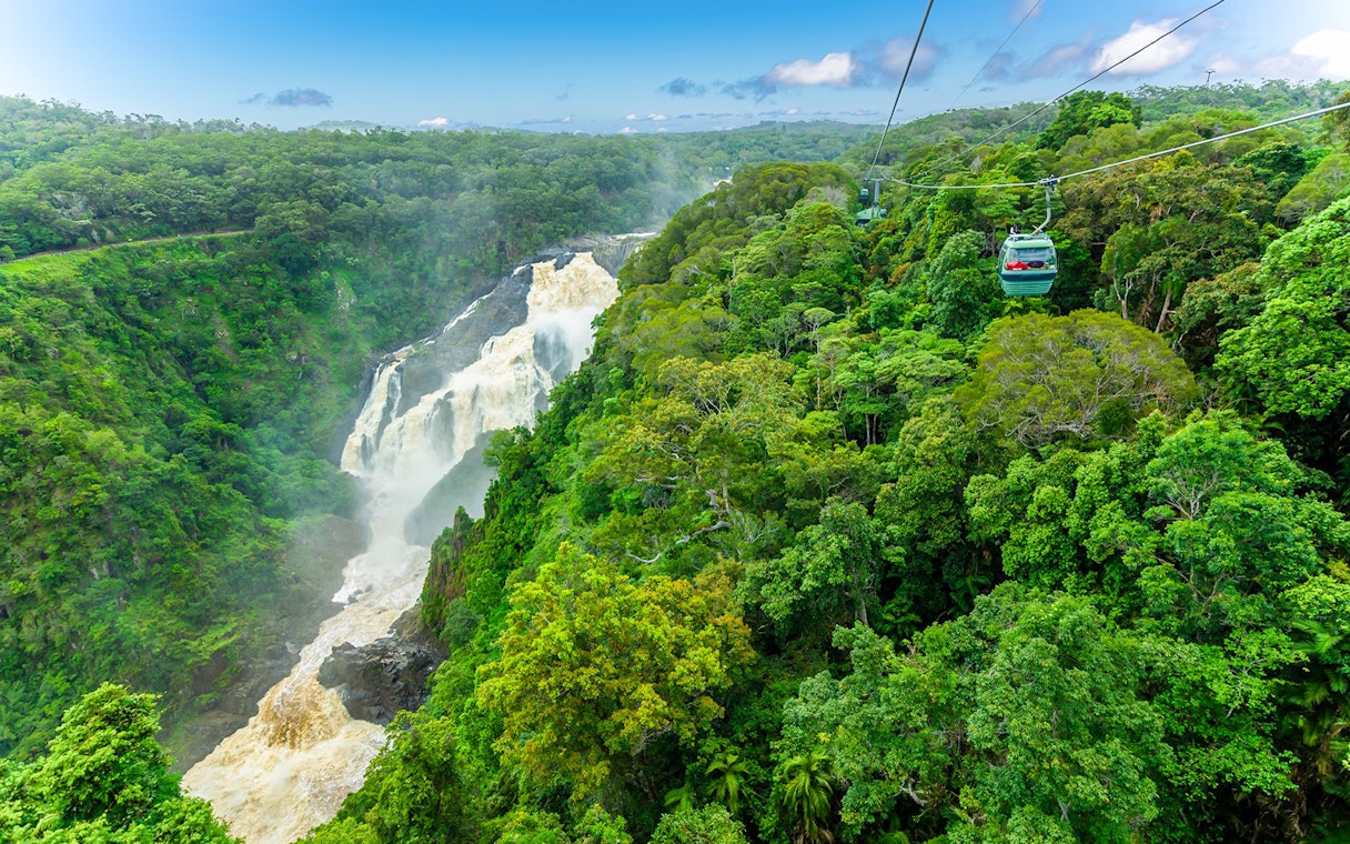 Skyrail cable car gliding over Kuranda Rainforest with waterfall view.