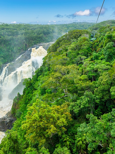 Skyrail cable car gliding over Kuranda Rainforest with waterfall view.