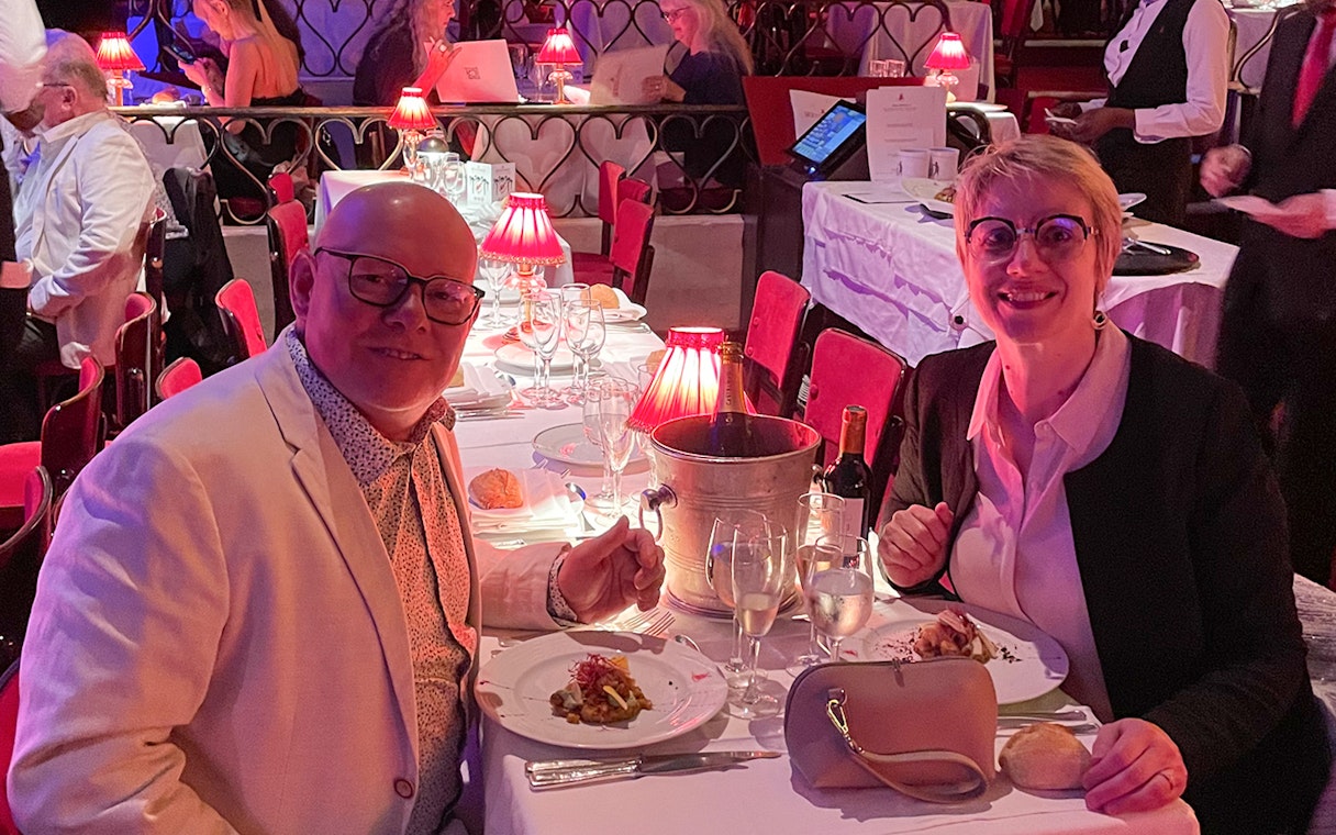 Couple dining at Moulin Rouge with wine and elegant table setting.