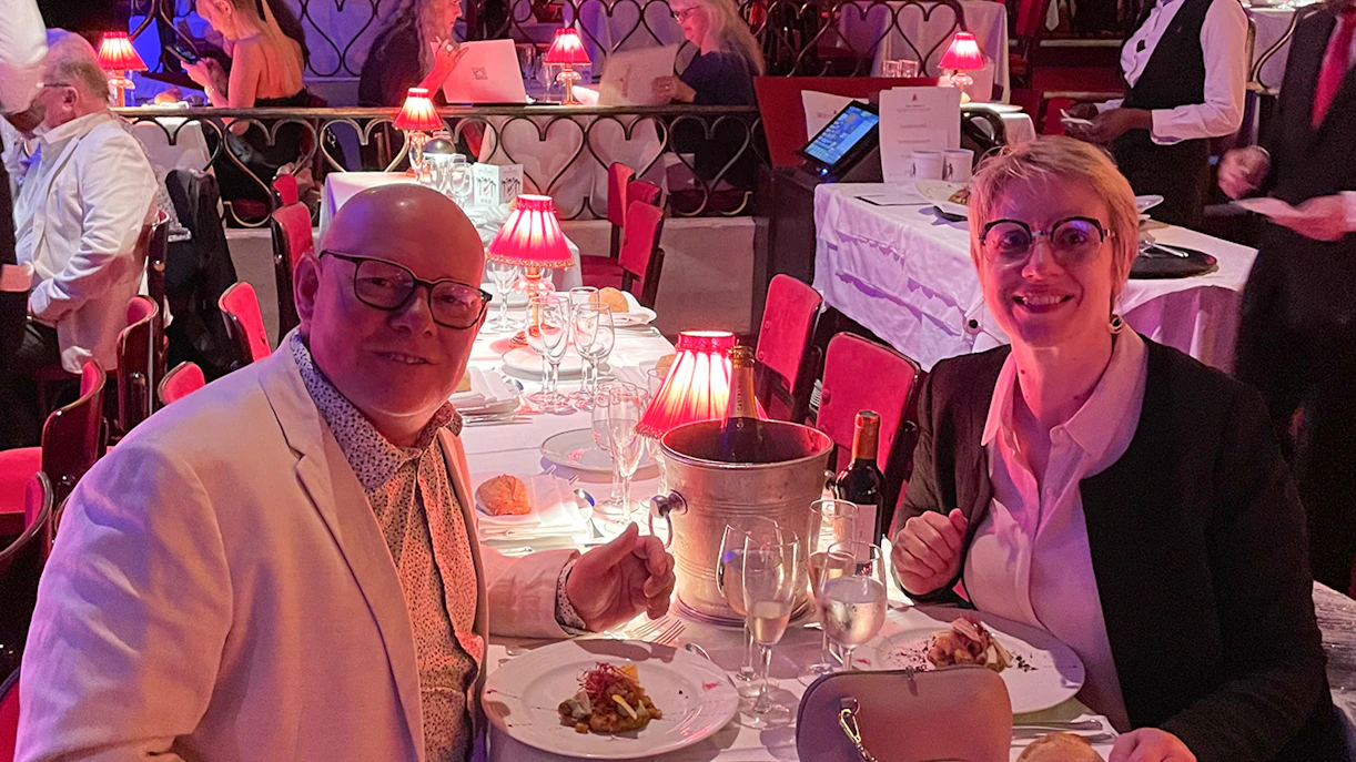 Couple dining at Moulin Rouge with wine and elegant table setting.