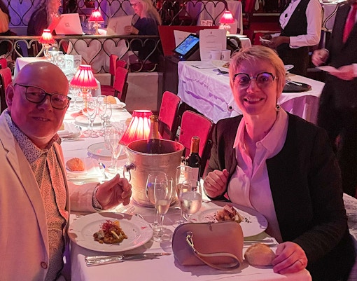 Couple dining at Moulin Rouge with wine and elegant table setting.