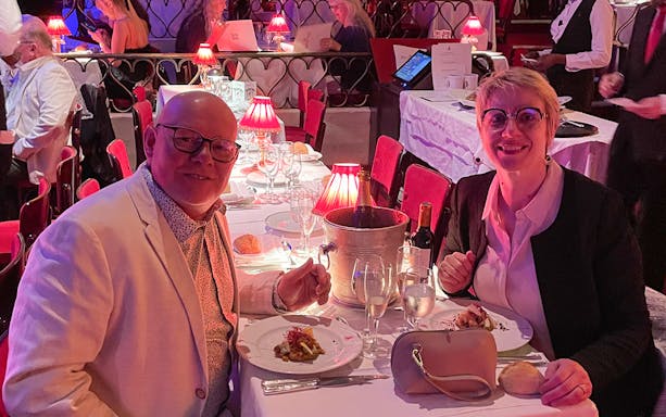 Couple dining at Moulin Rouge with wine and elegant table setting.
