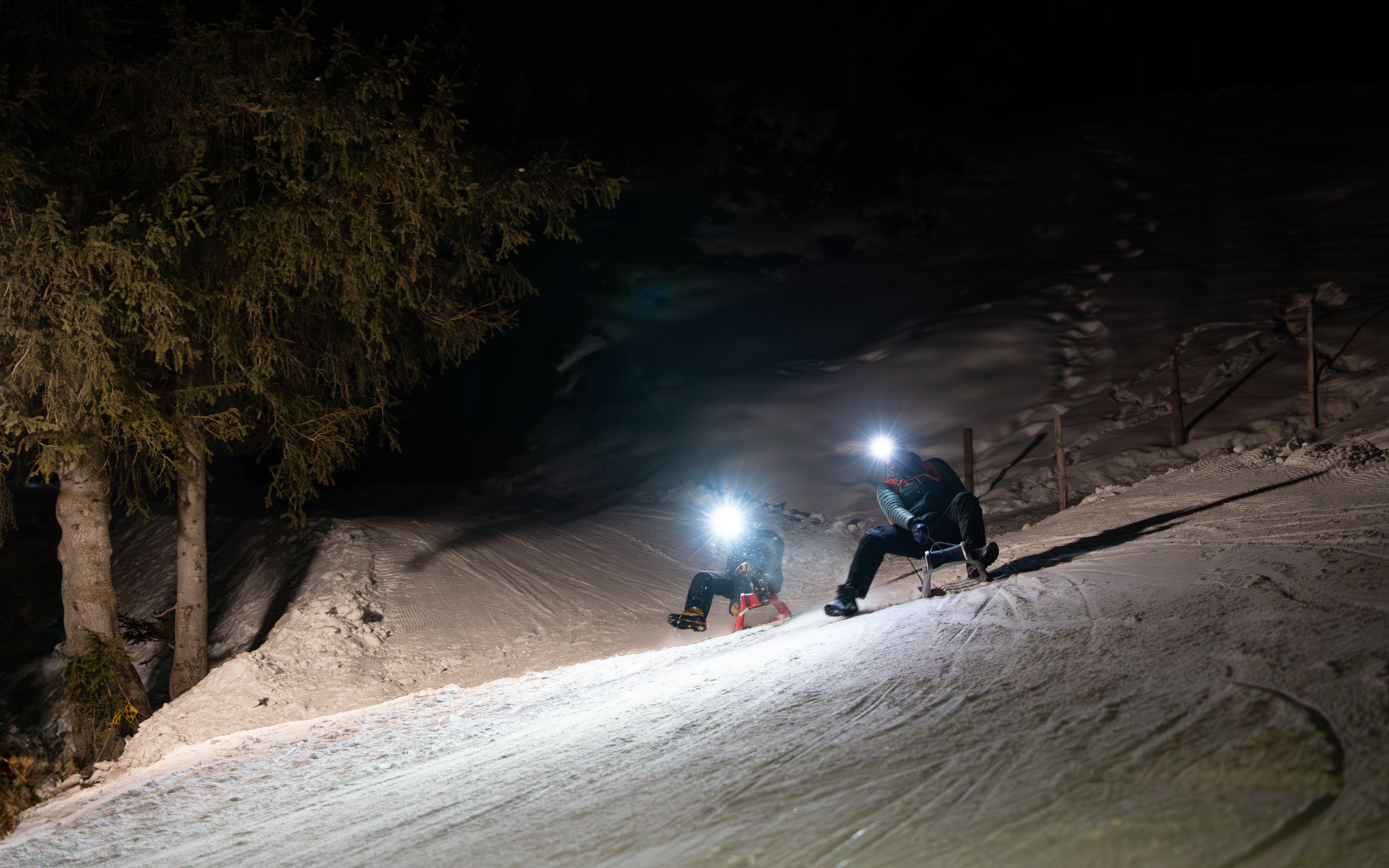 Group sledding at night with headlamps in snowy Interlaken.