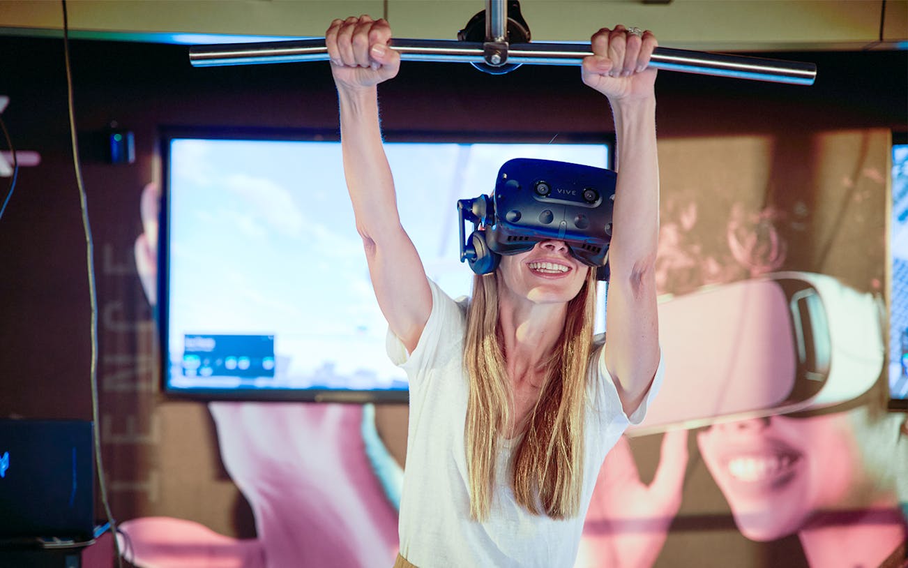 VR Plank experience at Melbourne Skydeck with participant using headset and holding bar.