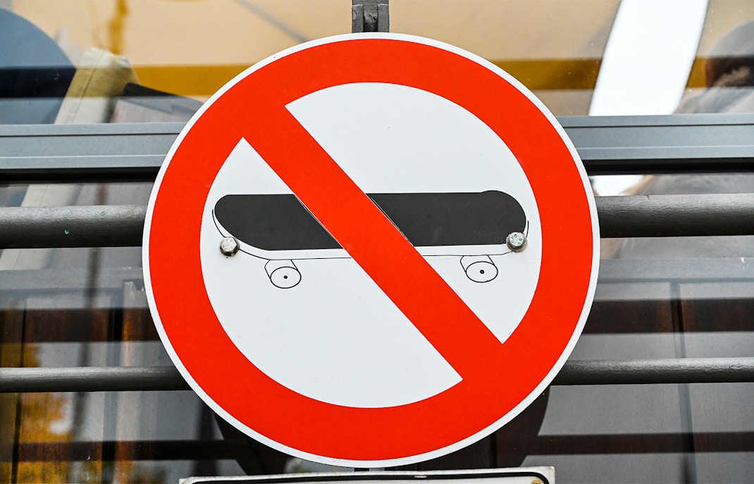 No skateboarding sign with red circle and slash over a skateboard.